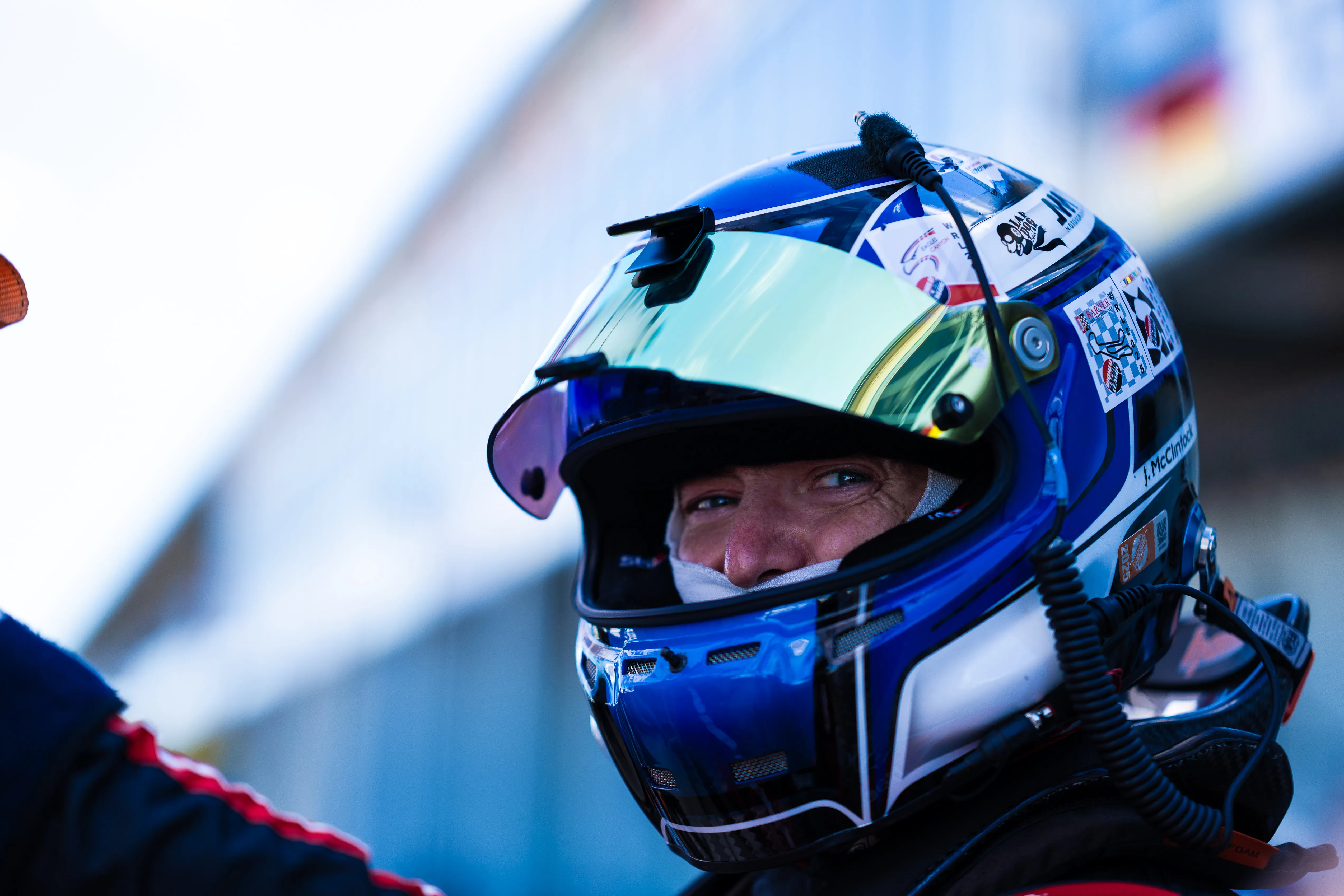 Jon McClintock in his blue helmet, visor raised, looking off to the side in pit lane.