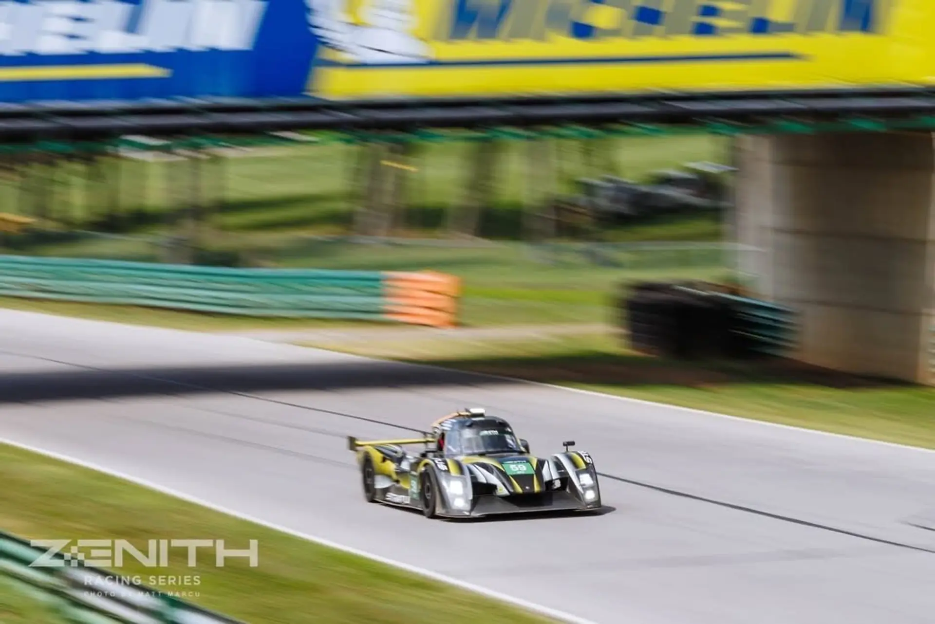 The black-and-yellow #59 Stratus prototype at speed under the bridge at VIR.