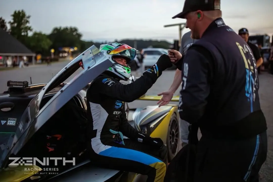 A driver climbs out of the #59 in the dusk light, fist-bumping a crew member as the changeover happens.