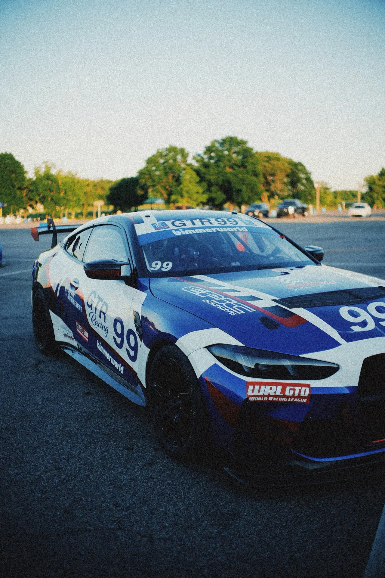 Team GTR's blue, white and red #99 BMW M4 GT4 in low evening light at VIR, front three-quarter.