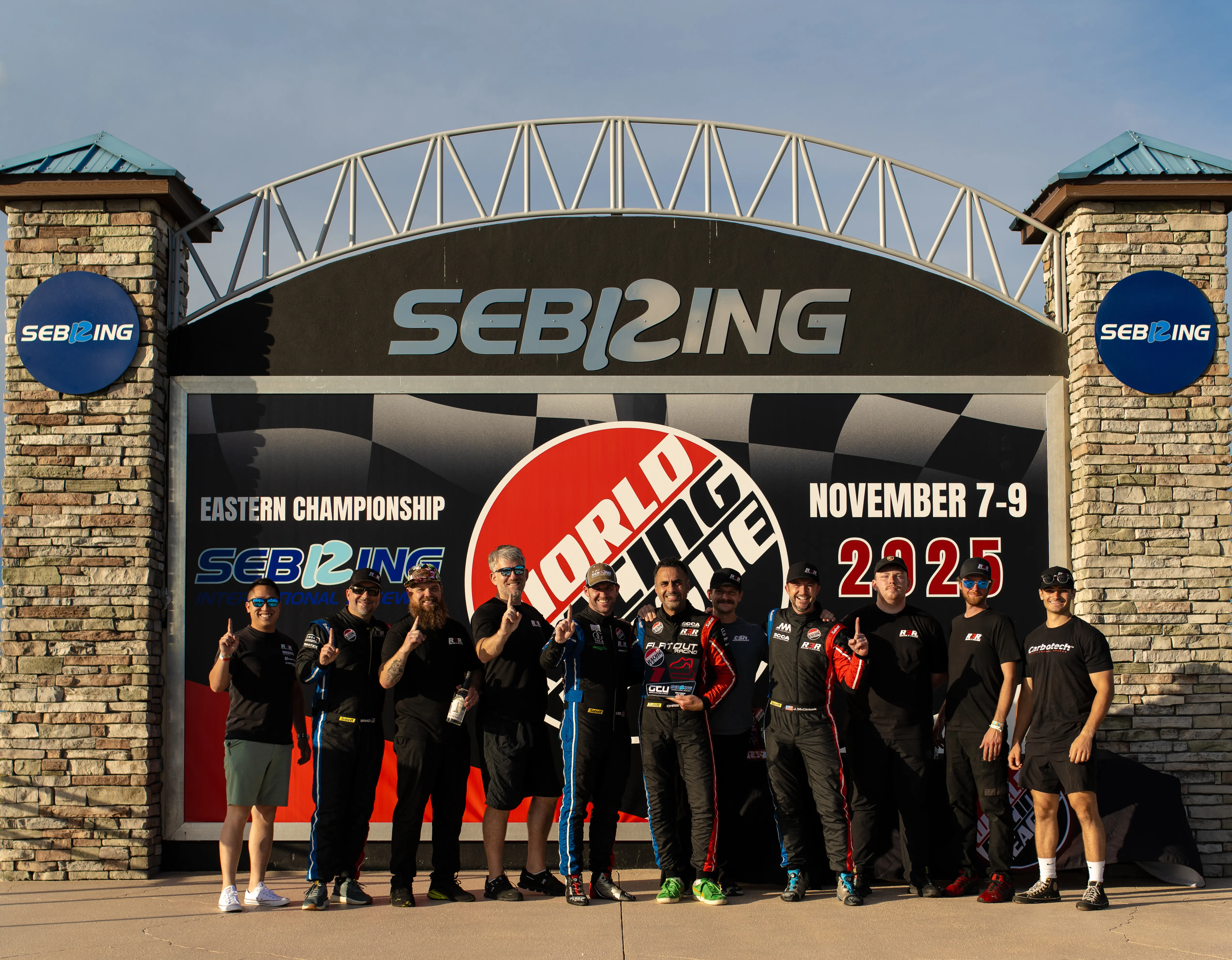 The Round 3 Racing team posed under the Sebring International Raceway entrance sign, World Racing League, November 2025.