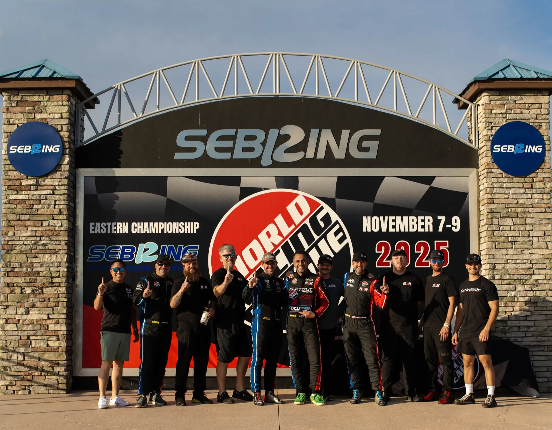 The Round 3 Racing team posed under the Sebring International Raceway entrance sign, World Racing League, November 2025.