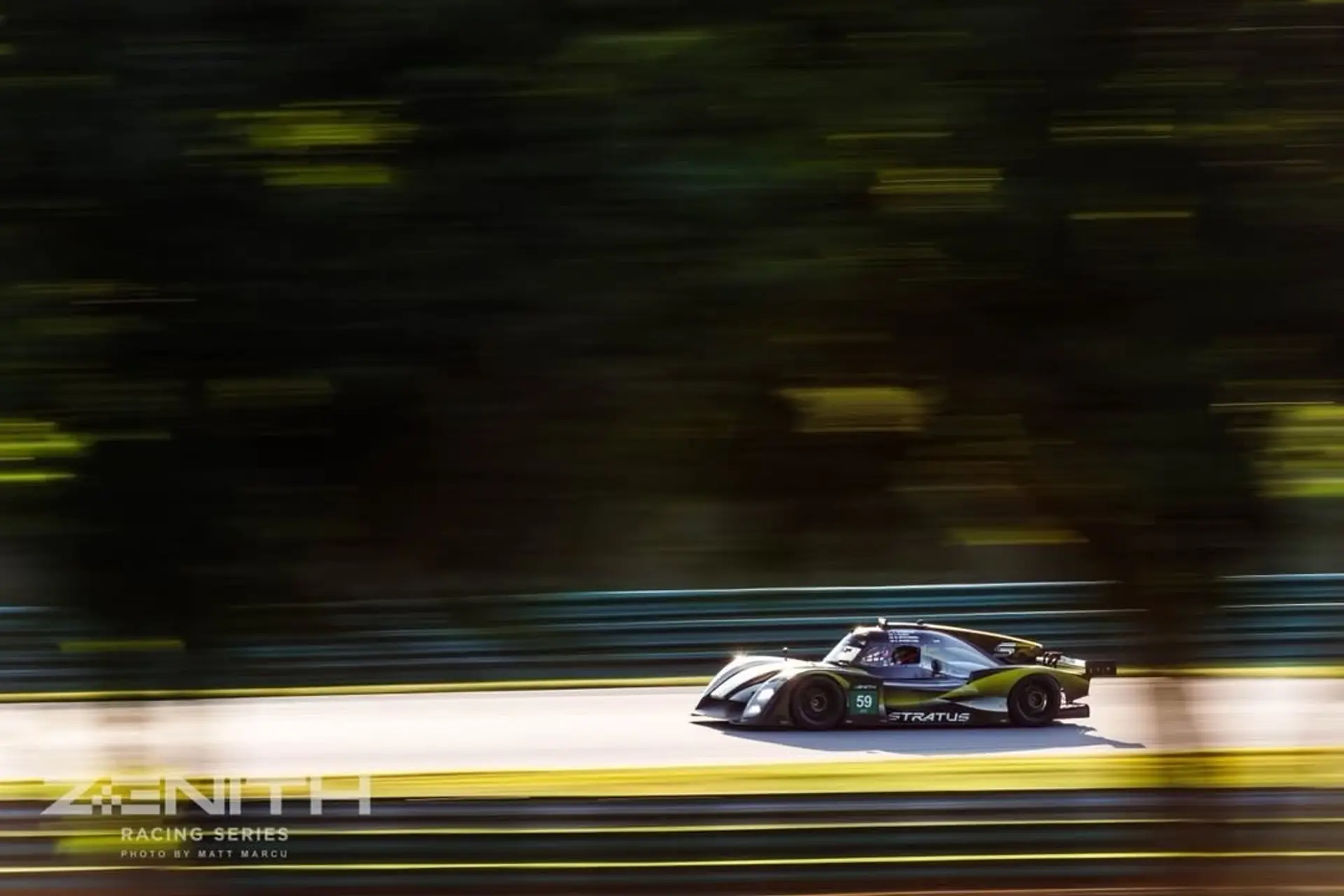 The #59 prototype backlit and panned along a tree-lined section of VIR, low evening light through the leaves.