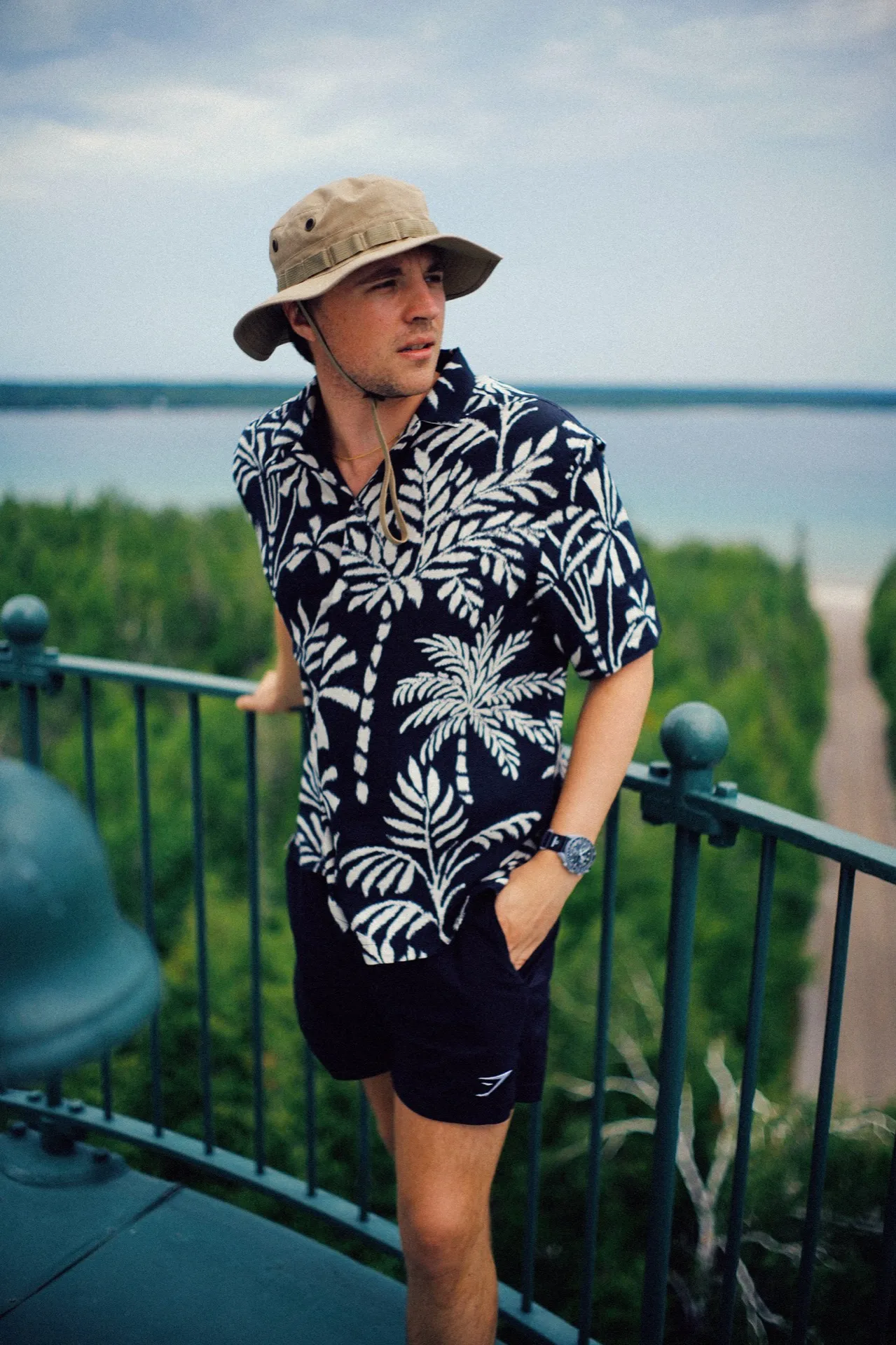 Randy Kinne in a bucket hat and palm-print shirt on a lakeside overlook.