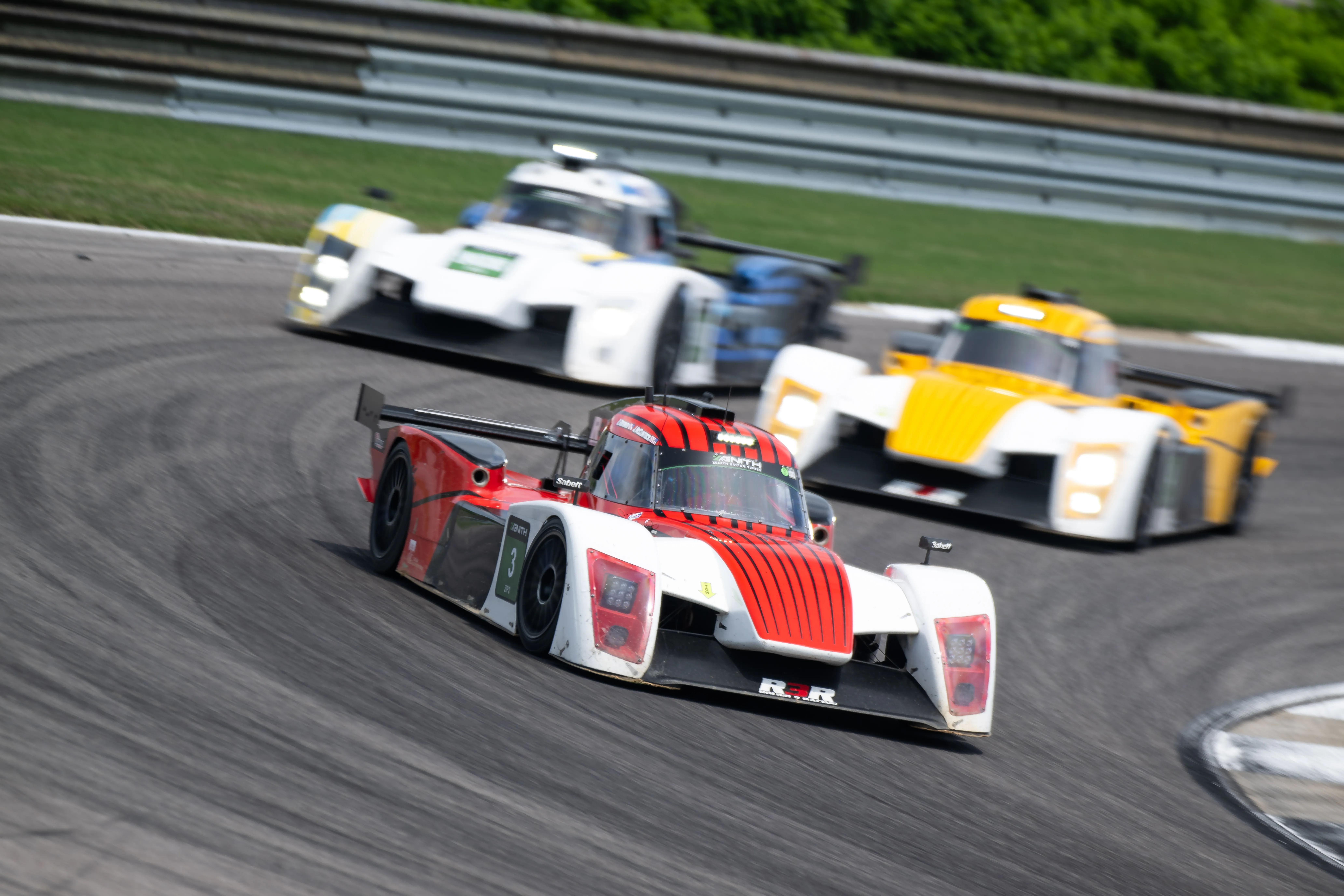 Round 3 Racing's red #3 leading a white prototype and a yellow prototype through a corner.