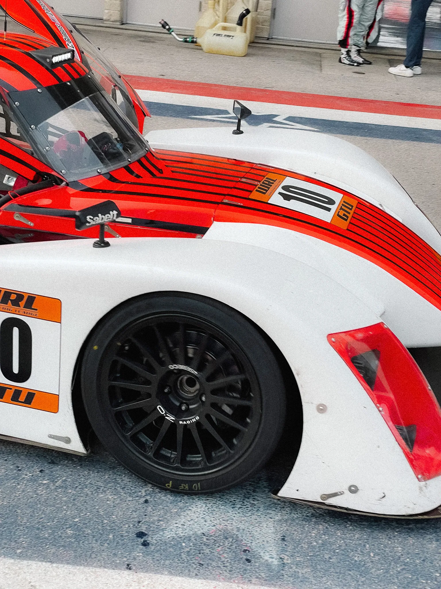 A Round 3 Racing NP01 close up in pit lane, white with red stripes, Sabelt branding visible.